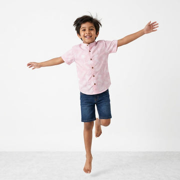 Child wearing a pink shirt and blue shorts on a white background